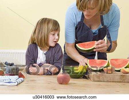 Stock Image - girl and mother with watermelon slices. Fotosearch