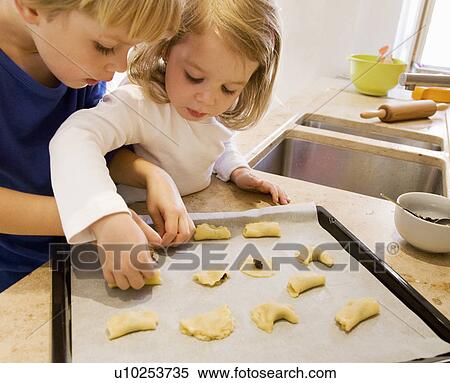 Stock Photography - girl, boy preparing cookies for baking. Fotosearch