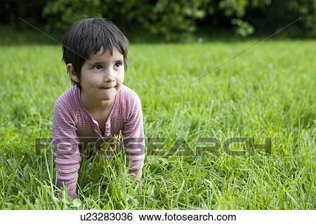 Stock Photograph - Girl crawling on all fours through grass. Fotosearch