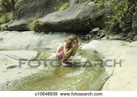 Stock Photo - Girl drinking water from stream. Fotosearch