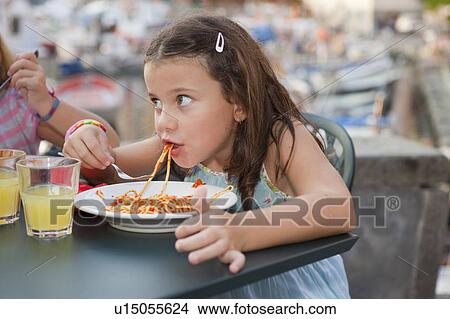 Picture - girl eating spaghetti. Fotosearch