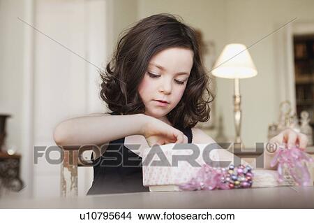 Picture - girl exploring contents of parcel. Fotosearch