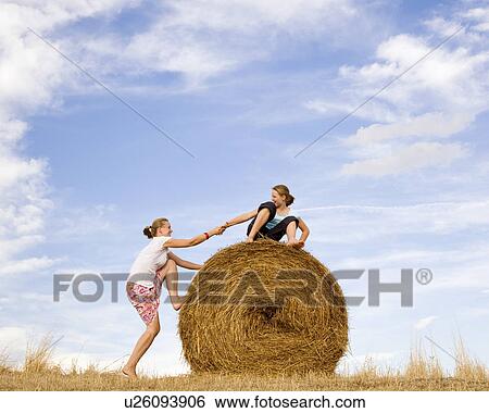 girl helping woman to climb hay bale View Large Photo Image Stock Photograph - girl helping woman to climb hay bale. Fotosearch