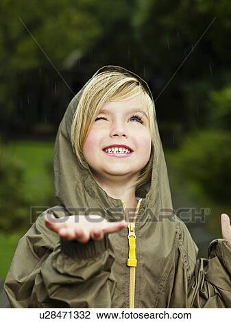 Stock Image - Girl holding her hand out to catch rain. Fotosearch
