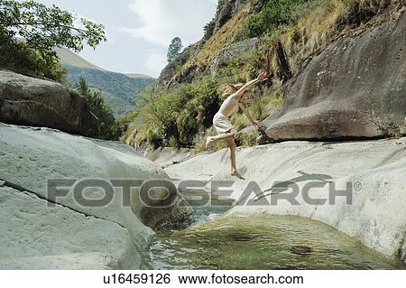 Girl jumping over stream View Large Photo Image Stock Photograph - Girl jumping over stream. Fotosearch