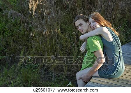 Stock Photo - Girl on boardwalk with arms around man. Fotosearch