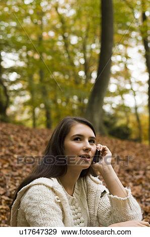 Stock Photo - girl on phone in woods. Fotosearch