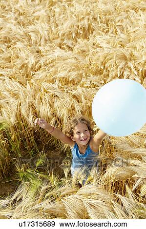 Stock Photo - Girl playing with balloon in wheat field. Fotosearch