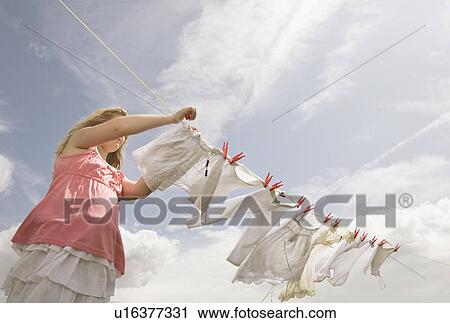 Stock Image - Girl putting clothing on a washing line. Fotosearch