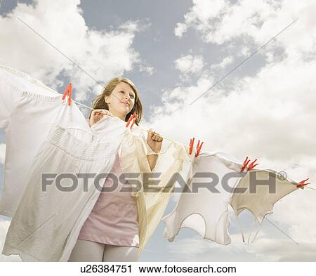 Stock Image - Girl putting clothing on a washing line. Fotosearch