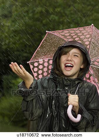 Stock Image - Girl singling holding an umbrella. Fotosearch