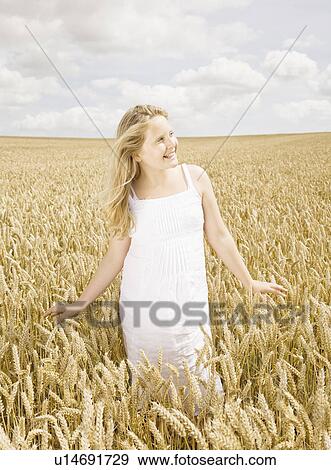 Girl standing in wheat field View Large Photo Image Stock Photo - Girl standing in wheat field. Fotosearch