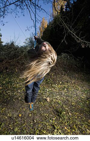 Girl standing on a tree swing View Large Photo Image Picture - Girl standing on a tree swing. Fotosearch