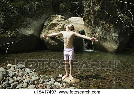 Girl standing on rock in stream View Large Photo Image Stock Photo - Girl standing on rock in stream. Fotosearch