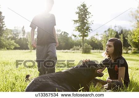 Girl stroking dog, boy in the back View Large Photo Image Picture - Girl stroking dog, boy in the back. Fotosearch