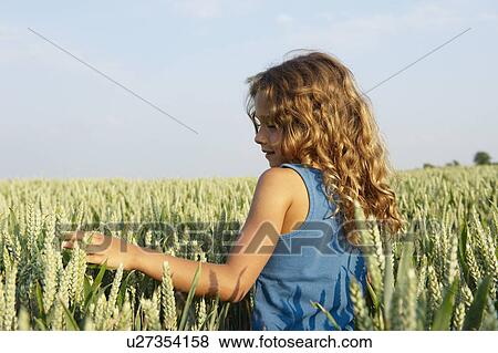 Stock Photo - Girl walking in a wheat field. Fotosearch