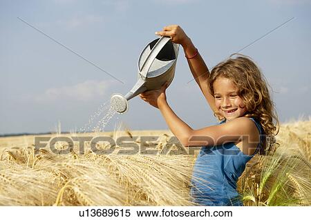 Girl watering a wheat field View Large Photo Image Stock Photography - Girl watering a wheat field. Fotosearch