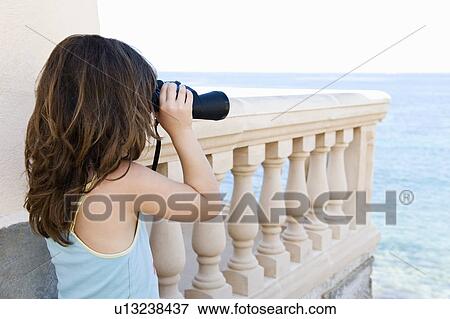 Stock Photo - Girl with binoculars looking out to sea. Fotosearch