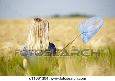Picture - Girl with butterfly net in a field. Fotosearch