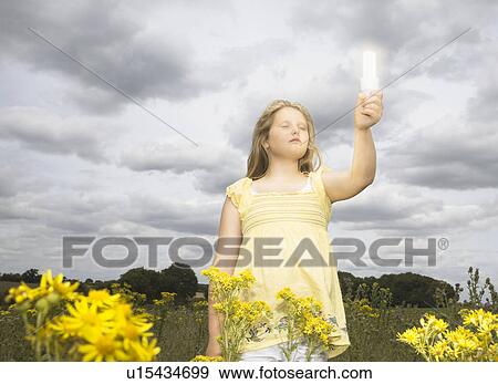 Girl with energy saver bulb in field View Large Photo Image Stock Photo - Girl with energy saver bulb in field. Fotosearch