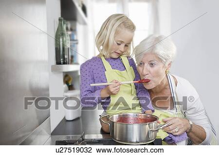 Stock Image - girl with grandmother cooking jam. Fotosearch