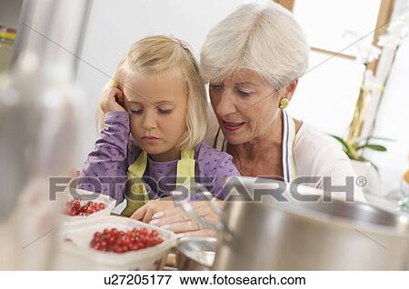 Stock Photo - girl with grandmother cooking jam. Fotosearch