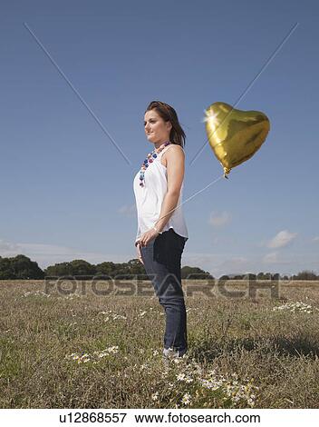 Girl with heart shaped balloon View Large Photo Image Stock Photo - Girl with heart shaped balloon. Fotosearch