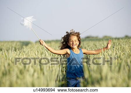 Girl with in a pinwheel in a field View Large Photo Image Picture - Girl with in a pinwheel in a field. Fotosearch