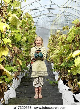 Stock Photo - Girl with plant in green house. Fotosearch