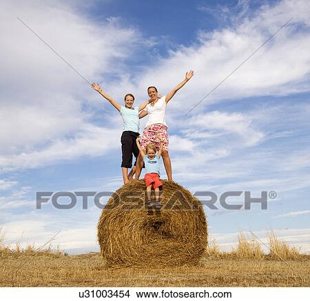 girl, woman, boy standing on hay bale View Large Photo Image Picture - girl, woman, boy standing on hay bale. Fotosearch