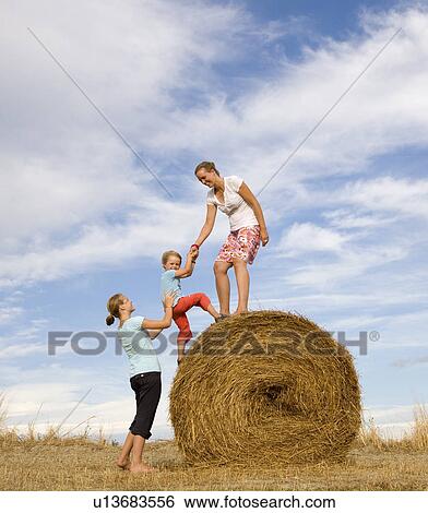 girl, woman help boy to climb hay bale View Large Photo Image Stock Photograph - girl, woman help boy to climb hay bale. Fotosearch