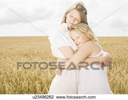Stock Image - Girls hugging in wheat field. Fotosearch