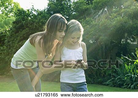 Girls looking at mobile phone View Large Photo Image Stock Photography - Girls looking at mobile phone. Fotosearch