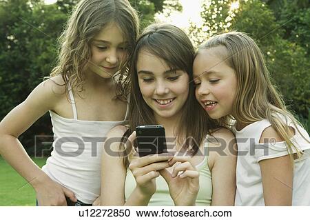 Stock Image - Girl's looking at photo on phone. Fotosearch