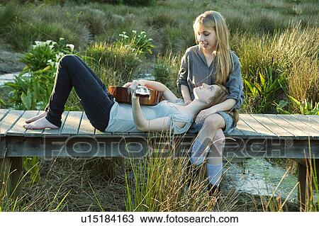 Stock Image - Girl's playing guitar on boardwalk. Fotosearch
