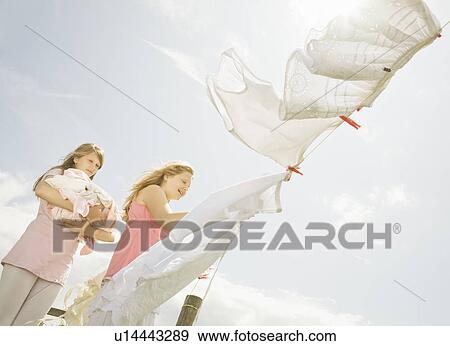 Stock Photo - Girls putting washing on a line. Fotosearch
