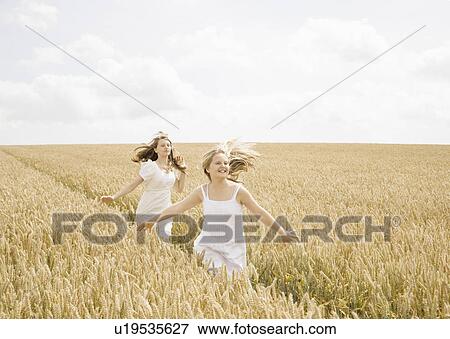 Stock Photo - Girls running in wheat field. Fotosearch