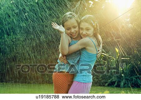 Girls standing in rain hugging View Large Photo Image Stock Photo - Girls standing in rain hugging. Fotosearch