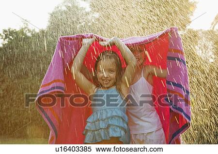 Girls standing under towel in rain View Large Photo Image Stock Photography - Girls standing under towel in rain. Fotosearch