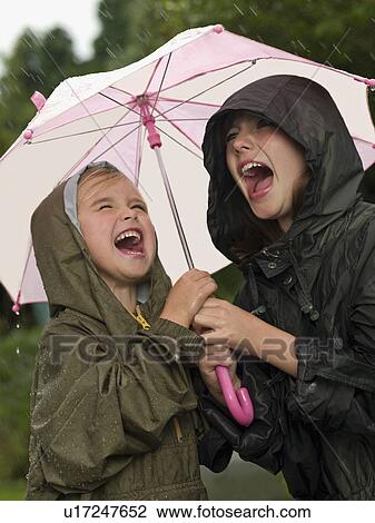 Stock Image - Girls under an umbrella singing. Fotosearch