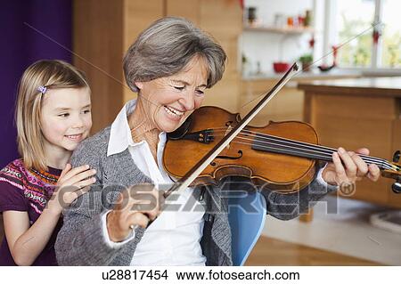 Picture - grandchild watching grandma making music. Fotosearch