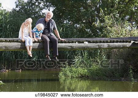 Stock Photo - grandfather and children on footbridge. Fotosearch