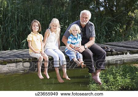 Stock Photo - grandfather and children on footbridge. Fotosearch