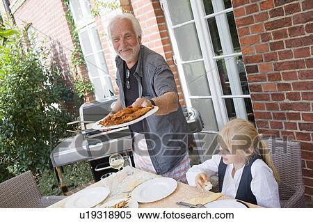 Stock Photography - grandfather barbecuing for children. Fotosearch