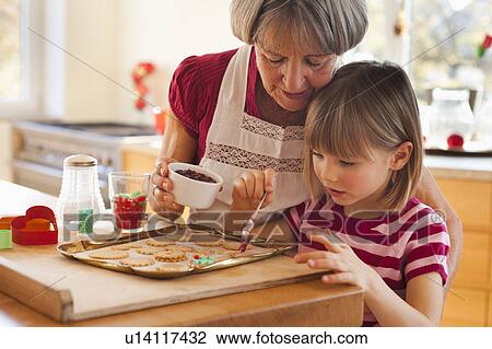 Stock Image - grandma and grandchild baking biscuits. Fotosearch