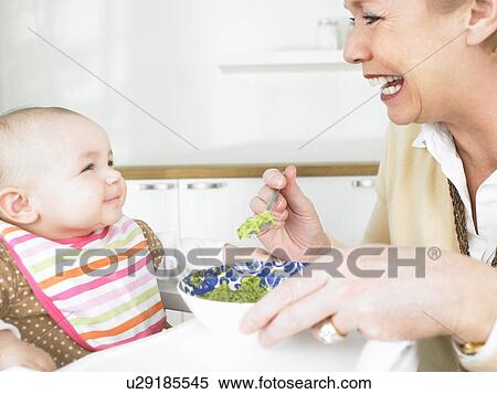 Stock Photography - Grandmother feeding baby. Fotosearch