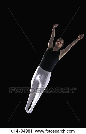Stock Image - gymnast outstretched in mid air. Fotosearch
