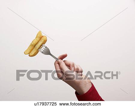 Stock Photography - Hand holding chips on a fork. Fotosearch