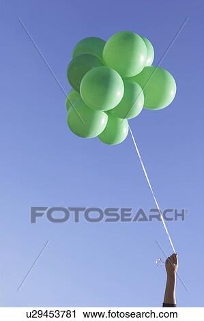 Stock Image -  hand holding green balloons. Fotosearch
