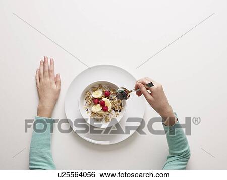 Stock Photograph - Hands by a bowl of cereal. Fotosearch